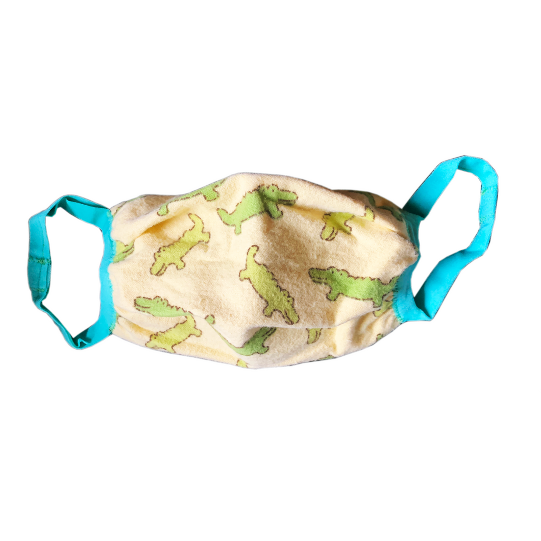 Tan face mask with crocodile pattern and sky blue ear loops on white background.
