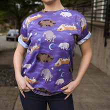 Load image into Gallery viewer, Model posing on sidewalk wearing dark blue jeans and purple t-shirt with cloud, crescent moon, heart, and star motifs surrounding 4 different sleeping dog breeds..