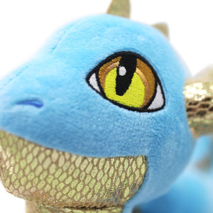 Closeup of Light blue and metallic gold detailed Skysong dragon plush stands, looking upward, with yellow and bronze eyes.
