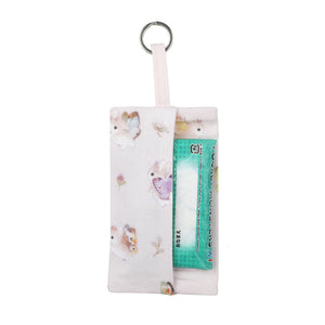 Pastel pink tissue holder holding small packet of tissues on white background.
