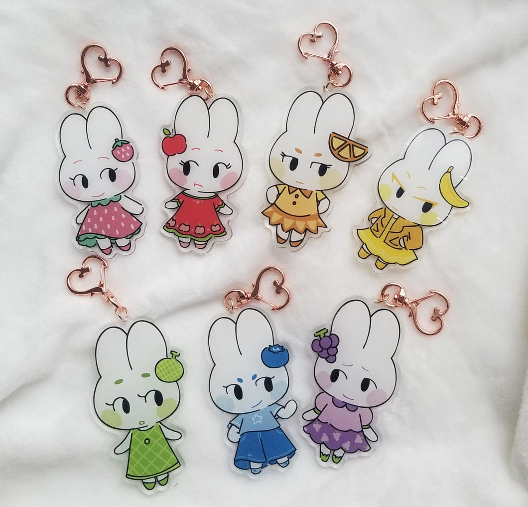 All fruit bunny acrylic charms on white blanket.
