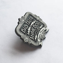 Load image into Gallery viewer, Tilted view of bad taste antique silver pin on white background.
