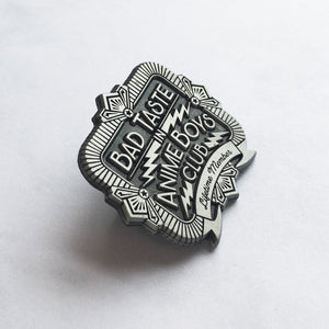 Tilted view of bad taste antique silver pin on white background.