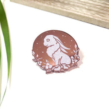 Load image into Gallery viewer, Sparkly white and gold enamel pin depicting sitting rabbit with flowers. 