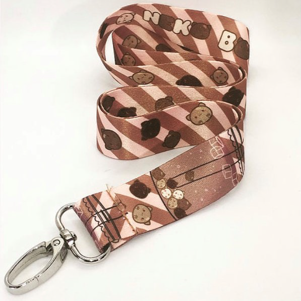 Brown, tan, and cream neko boba striped lanyard with silver clasp on white background.