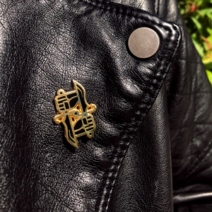 Dual Wield Studio logo lapel pin on black leather jacket lapel.