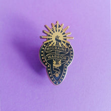 Load image into Gallery viewer, A black and gold enamel pin with design depicting a ribbon wrapped around a sword and sun, reading &quot;Migraine Warrior&quot; on purple background.