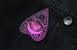 Black planchette patch with magenta detailing on black denim.