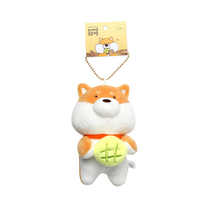 Tan and white shiba with green roll keyring hanging from tag on white background.