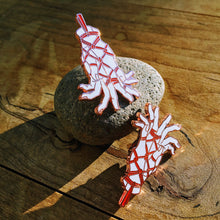 Load image into Gallery viewer, Two rose gold pins depicting hands tenderly tied with rope on red backing card on a stone resting on a wooden table.