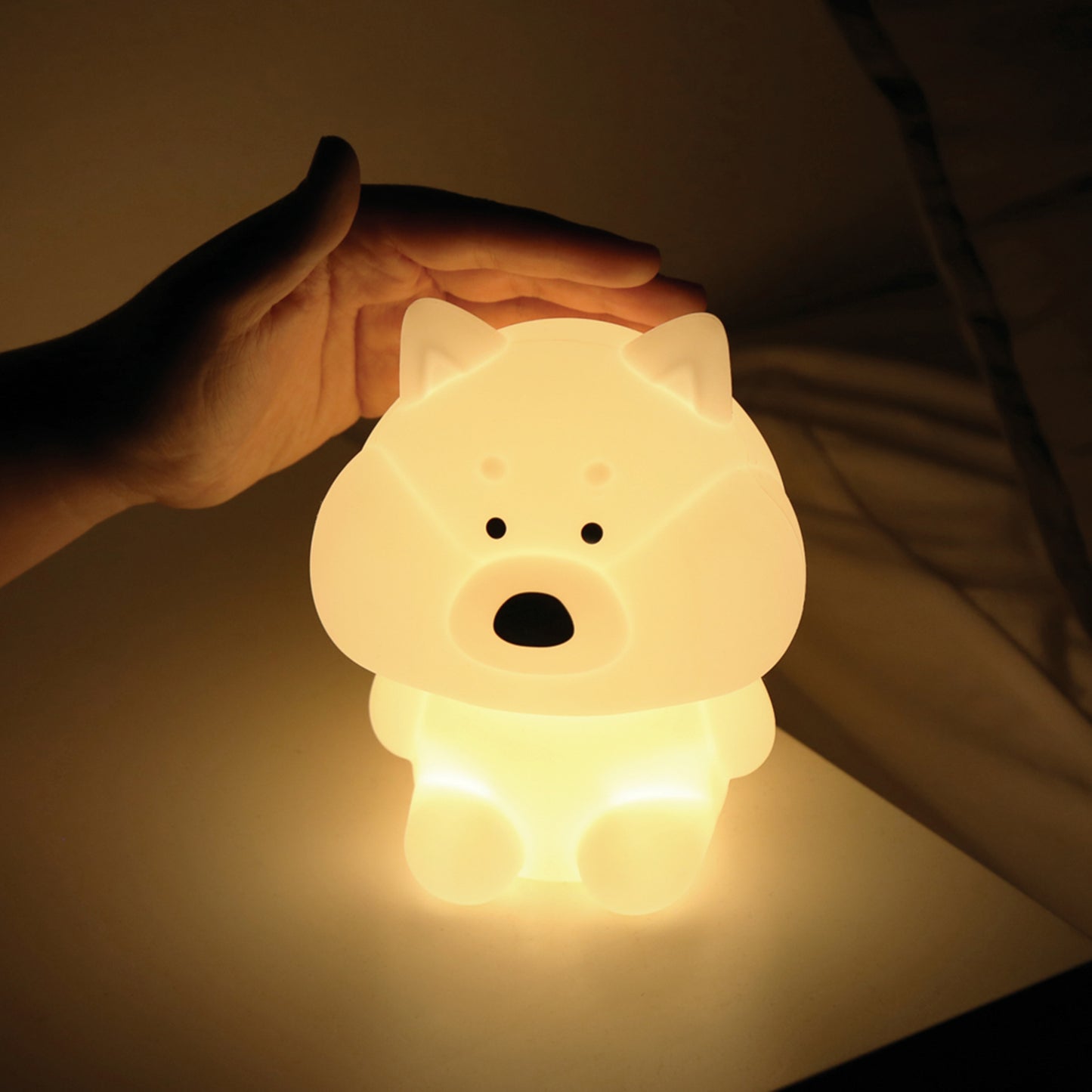 Model is softly petting the glowing shiba mood lamp on their bedside table.