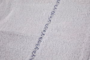 Closeup of white lining, sewn with decorative leafy vine stitch.