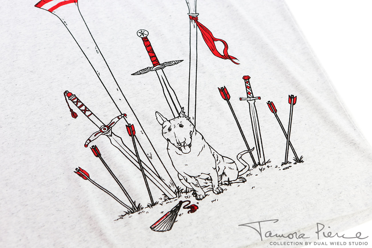 Closeup of light grey t-shirt, showing black and red outlined weapons embedded in the ground around a sitting Jump the dog.