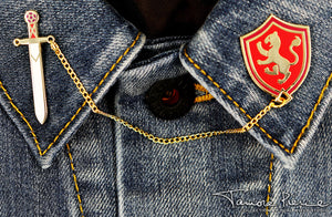 Alanna Sword and Shield pins on each lapel across a denim shirt.