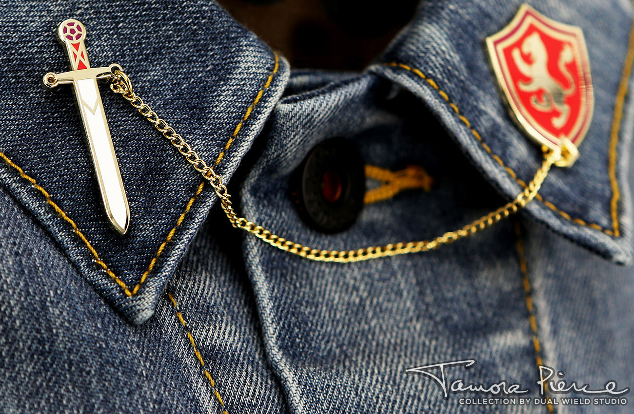 Angled view of Sword and Shield pins worn on denim lapels.