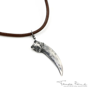 Silver badger claw pendant on brown necklace cord on white background.