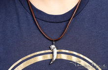 Load image into Gallery viewer, Model wearing silver badger claw pendant on brown necklace cord on white background.