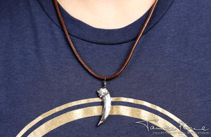 Model wearing silver badger claw pendant on brown necklace cord on white background.