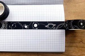 Strip of washi tape along gridded journal page on wooden table.